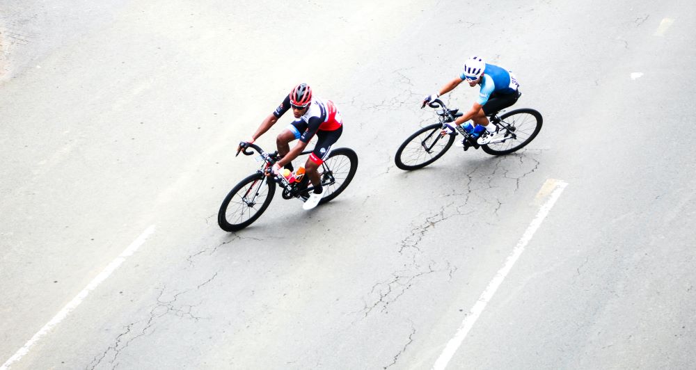 two men racing bicycles on a road