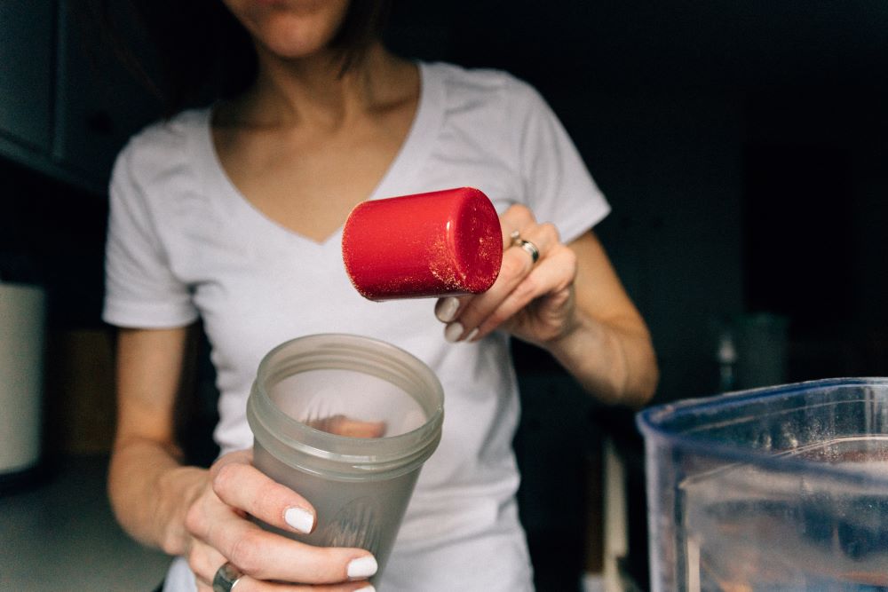 Women fills shaker with protein