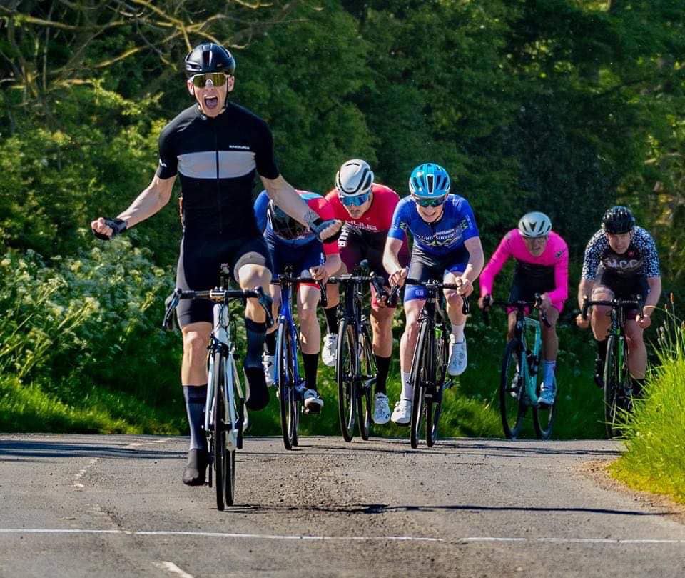 Alexander Macrae raises his arms in victory as he wins a cycling race